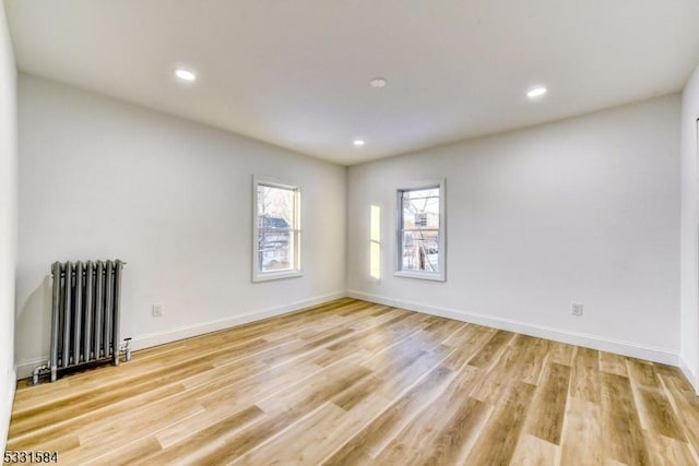 spare room featuring radiator heating unit and light hardwood / wood-style flooring