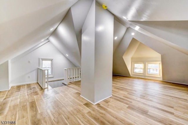 additional living space with vaulted ceiling and light hardwood / wood-style flooring