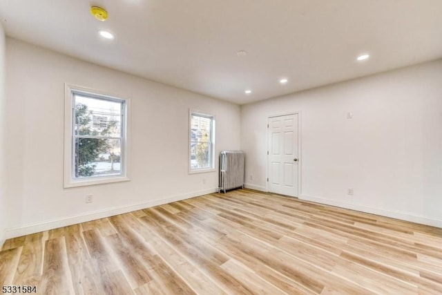 empty room featuring radiator heating unit and light wood-type flooring