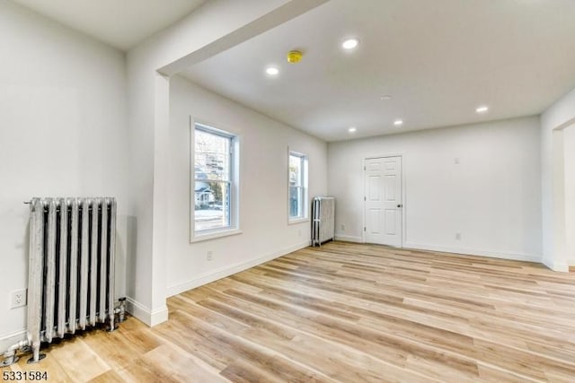 unfurnished room with radiator and light hardwood / wood-style flooring