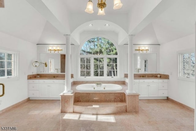 bathroom featuring high vaulted ceiling, a relaxing tiled tub, vanity, and ornate columns