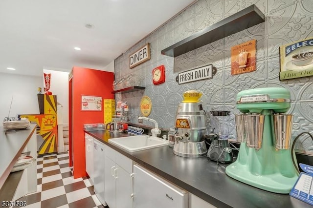 kitchen with sink, white dishwasher, and white cabinetry