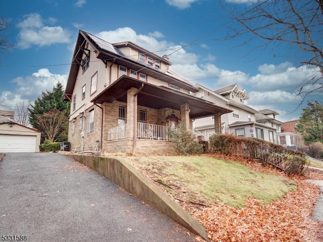 view of front of house with covered porch, an outbuilding, a garage, and a front yard