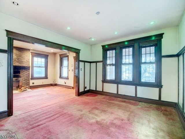 unfurnished living room featuring light carpet and a brick fireplace