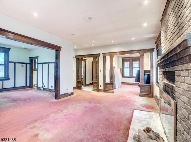 unfurnished living room with light colored carpet, ornate columns, and a fireplace