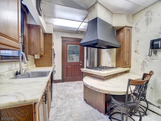 kitchen featuring a kitchen breakfast bar, island exhaust hood, sink, and stainless steel gas cooktop