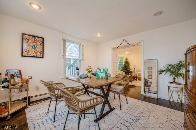 dining area featuring dark wood-type flooring and a baseboard heating unit