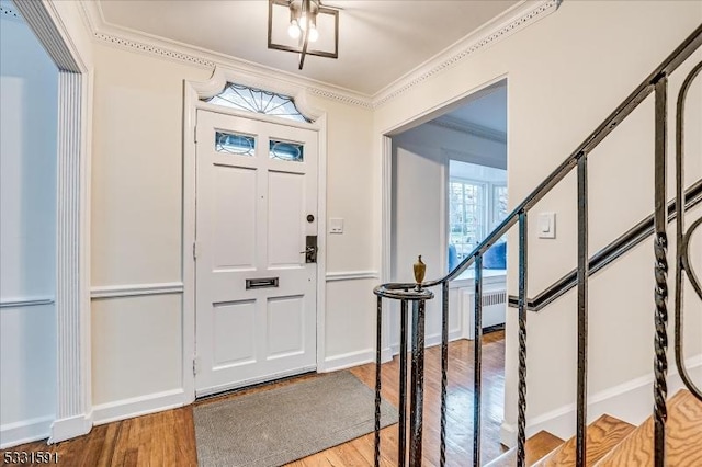 entrance foyer featuring hardwood / wood-style floors, ornamental molding, and radiator heating unit