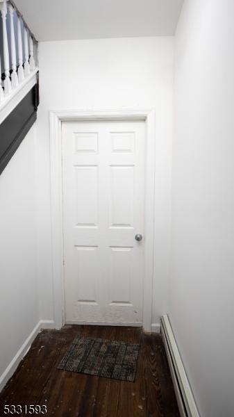 doorway with a baseboard heating unit, baseboards, and wood finished floors