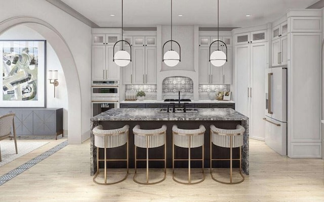 kitchen featuring sink, stainless steel appliances, a center island with sink, and dark stone countertops