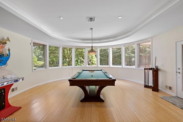 recreation room with a tray ceiling, billiards, and light hardwood / wood-style flooring