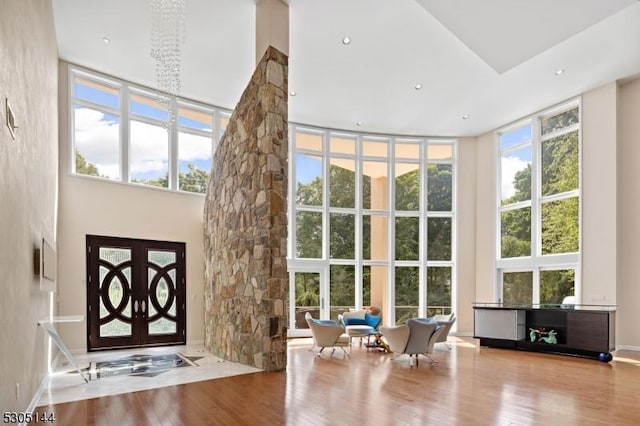 foyer with light wood-type flooring, an inviting chandelier, a wealth of natural light, and a high ceiling