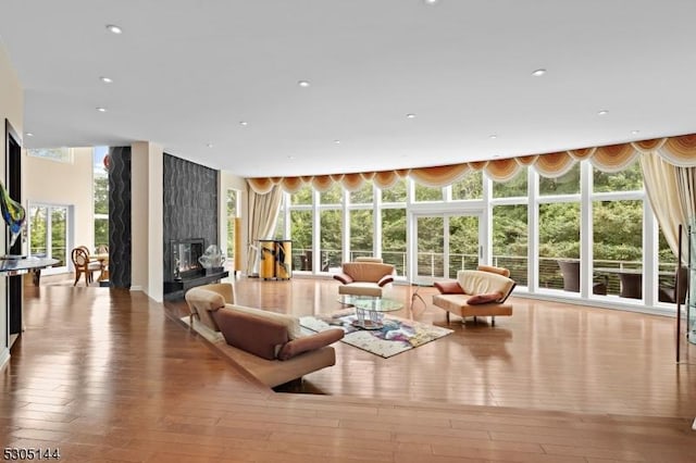 living room with light wood-type flooring, a premium fireplace, and a wall of windows