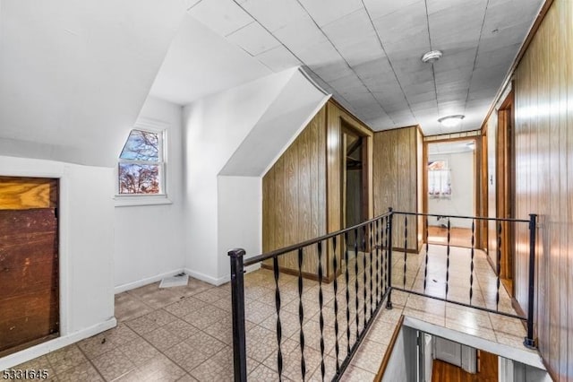 hall featuring lofted ceiling and wooden walls