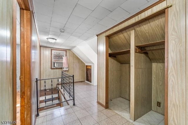 additional living space with cooling unit, lofted ceiling, and wooden walls