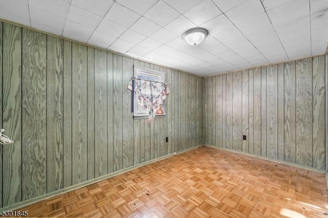 unfurnished room featuring wooden walls and light parquet flooring