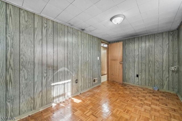 unfurnished room with light parquet floors and wooden walls