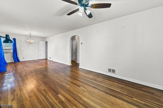 empty room featuring ceiling fan with notable chandelier and dark hardwood / wood-style floors