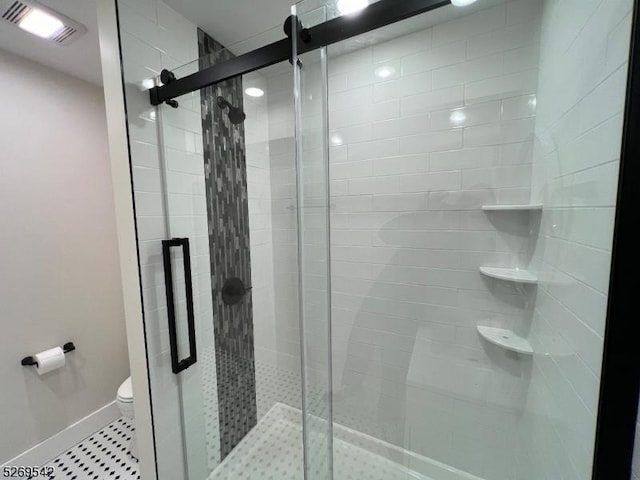 bathroom with tile patterned flooring, toilet, and a shower with door