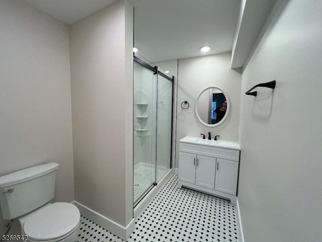 bathroom featuring vanity, a shower with shower door, and toilet