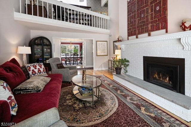 living room featuring a high ceiling, a fireplace, and hardwood / wood-style flooring