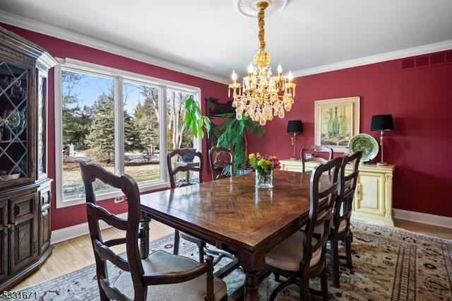 dining space featuring a chandelier, light wood-type flooring, and ornamental molding