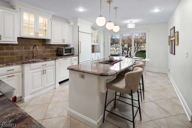 kitchen featuring sink, a kitchen island, white cabinetry, and pendant lighting