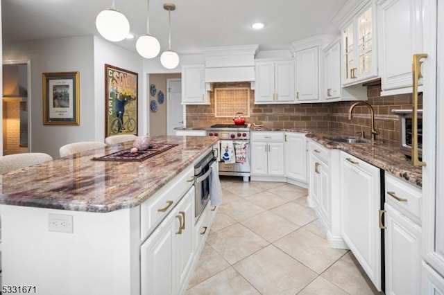 kitchen featuring appliances with stainless steel finishes, white cabinetry, dark stone countertops, and a center island