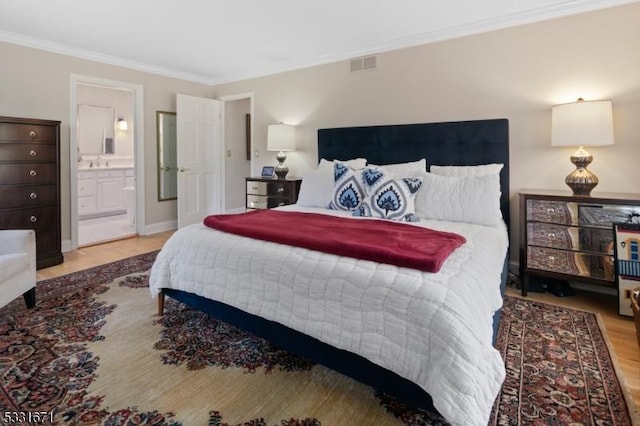 bedroom with hardwood / wood-style flooring, crown molding, and connected bathroom