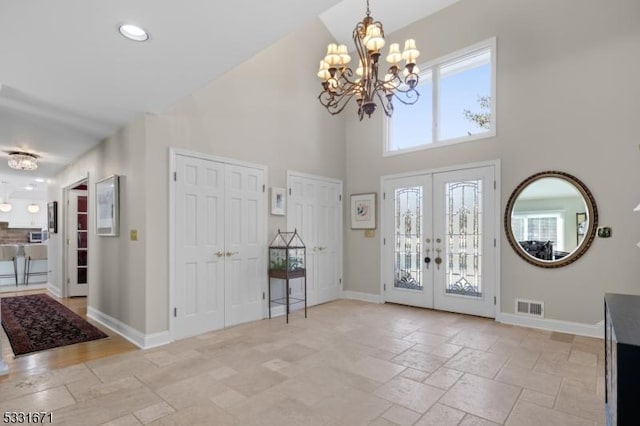 foyer entrance featuring a notable chandelier, french doors, high vaulted ceiling, and plenty of natural light