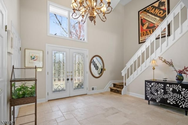 entrance foyer with a towering ceiling, french doors, and a chandelier