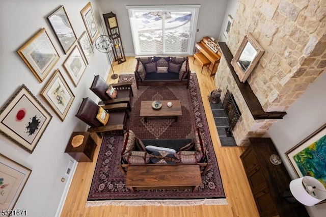 living room featuring a towering ceiling, hardwood / wood-style flooring, and a stone fireplace