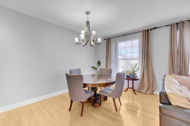 dining area with light hardwood / wood-style flooring and a notable chandelier