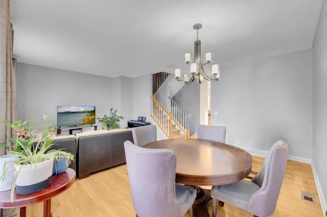 dining area with light hardwood / wood-style flooring and a chandelier