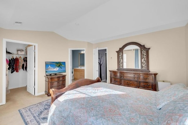 bedroom featuring ensuite bathroom, light colored carpet, a spacious closet, a closet, and lofted ceiling