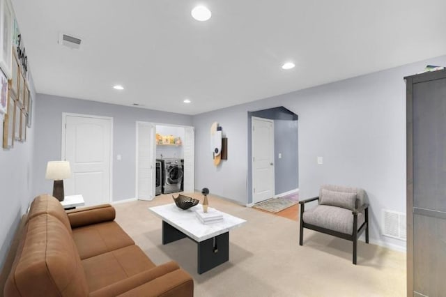 carpeted living room featuring washer and clothes dryer