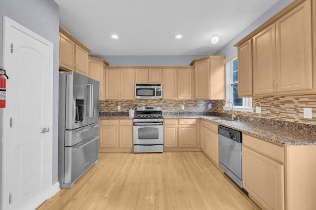 kitchen with decorative backsplash, appliances with stainless steel finishes, light wood-type flooring, sink, and light brown cabinets