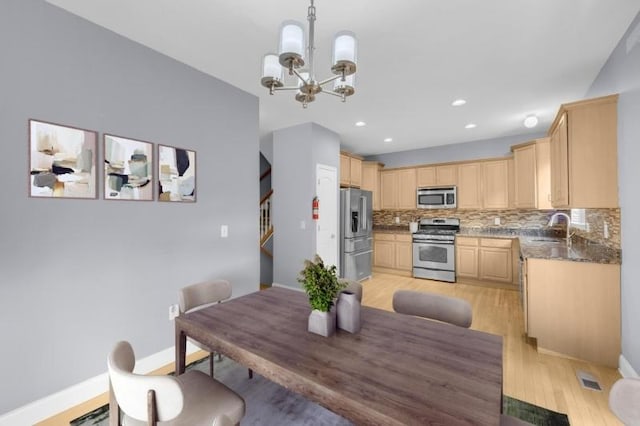 dining area featuring a notable chandelier, light hardwood / wood-style floors, and sink