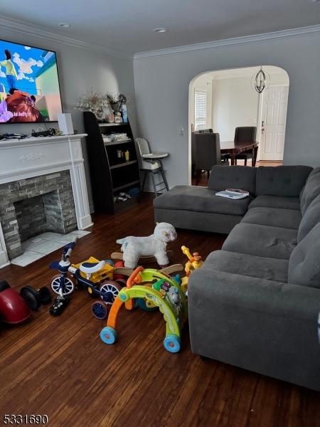 living room with a fireplace, wood-type flooring, and ornamental molding