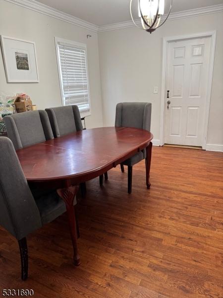 dining area featuring hardwood / wood-style floors, crown molding, and an inviting chandelier