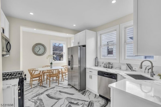 kitchen with light stone counters, sink, white cabinetry, and stainless steel appliances