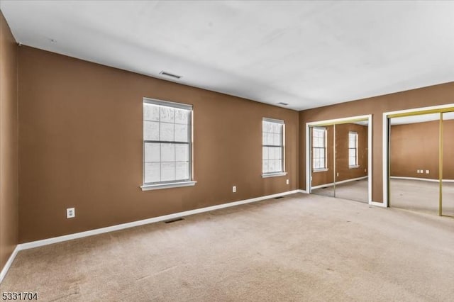 unfurnished bedroom with two closets and carpet