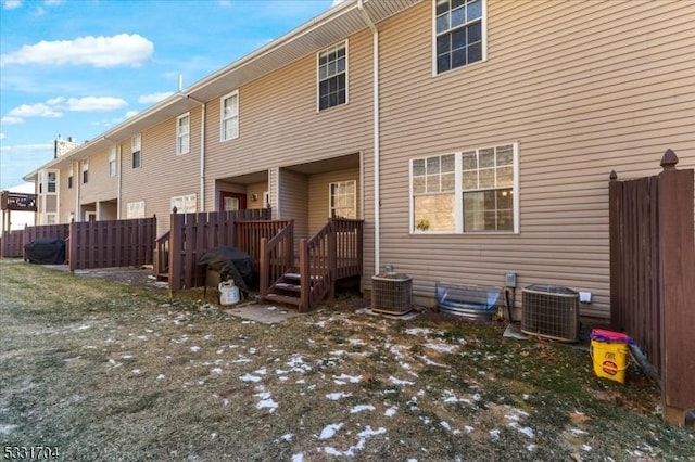 back of property with central AC and a yard