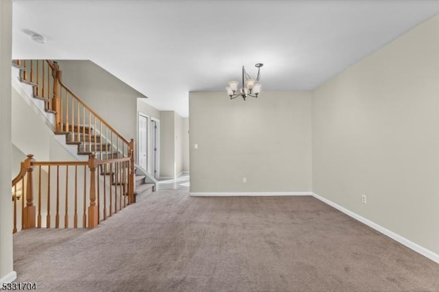 carpeted spare room featuring a chandelier