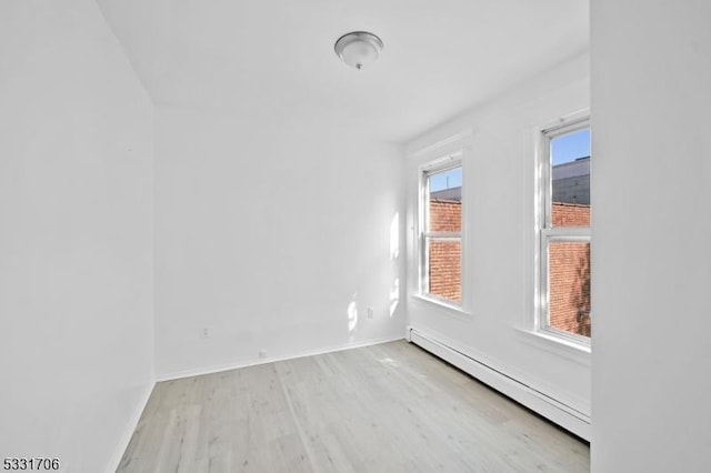 empty room featuring baseboard heating and light wood-type flooring