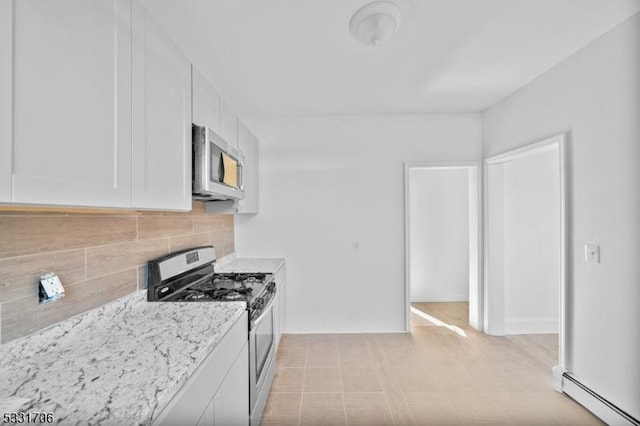 kitchen featuring light stone countertops, tasteful backsplash, white cabinetry, stainless steel appliances, and a baseboard radiator