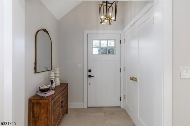 foyer with light tile patterned floors, vaulted ceiling, and an inviting chandelier