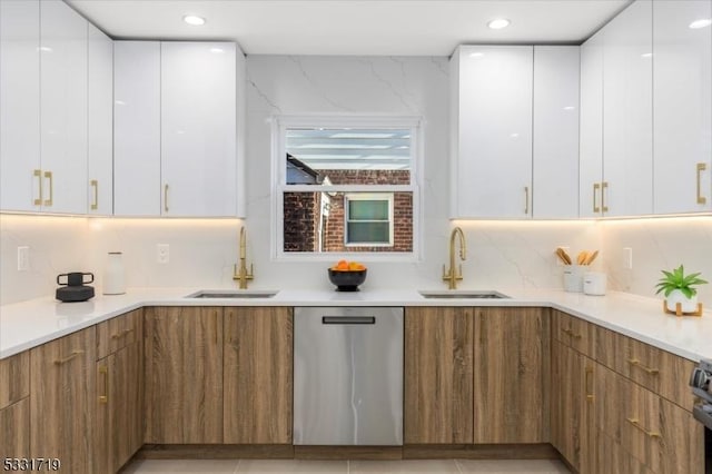 kitchen with dishwasher, white cabinetry, and sink