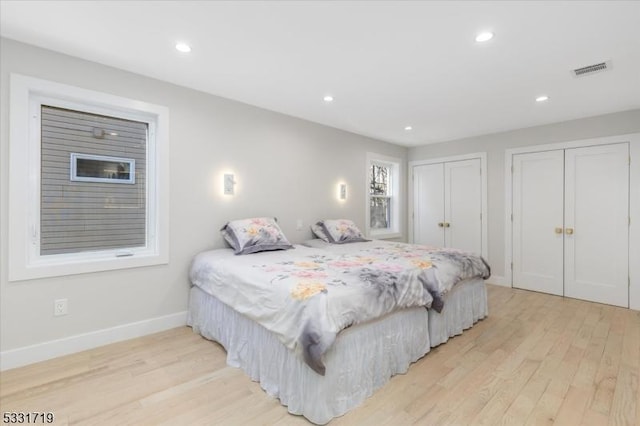 bedroom featuring light wood-type flooring and two closets