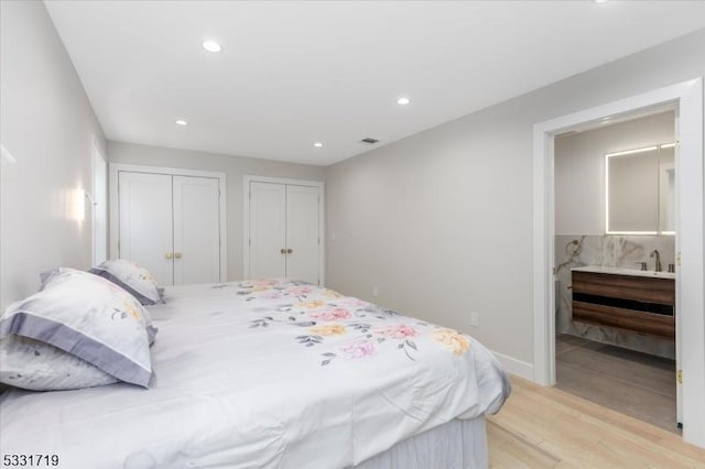 bedroom featuring light wood-type flooring and two closets